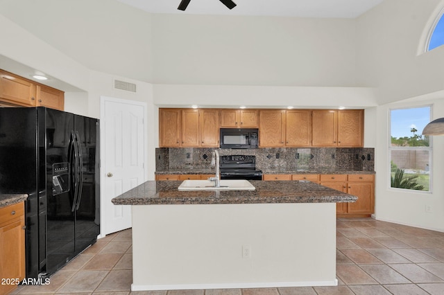 kitchen featuring black appliances, decorative backsplash, a sink, light tile patterned floors, and a towering ceiling