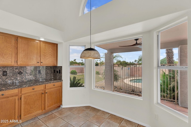 kitchen with tasteful backsplash, ceiling fan, decorative light fixtures, baseboards, and brown cabinets