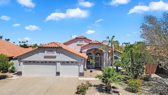 mediterranean / spanish-style house with an attached garage, a tile roof, concrete driveway, stucco siding, and fence