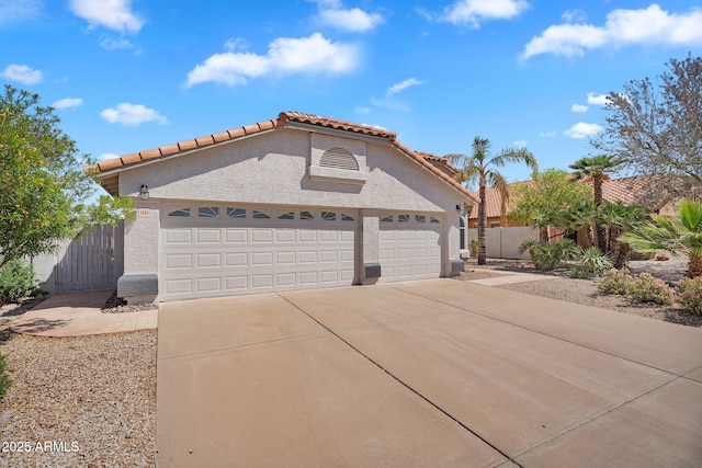 view of front of house featuring stucco siding, concrete driveway, a tiled roof, fence, and a garage