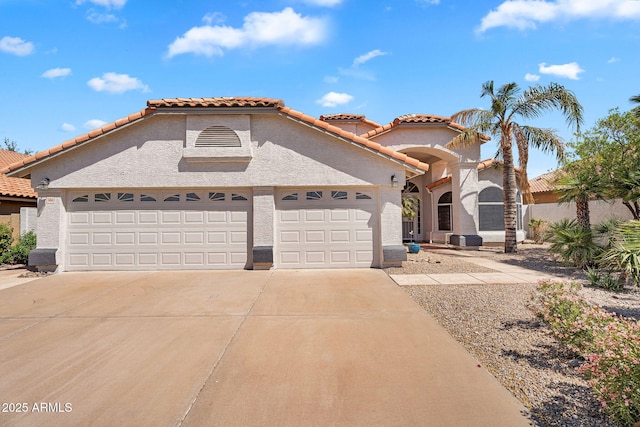 mediterranean / spanish-style house featuring stucco siding, concrete driveway, an attached garage, and a tiled roof
