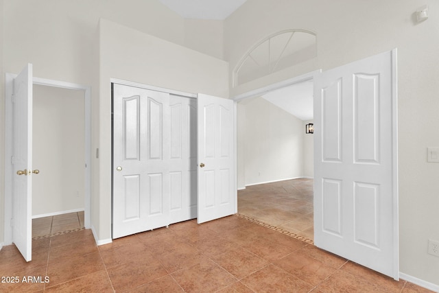 unfurnished bedroom featuring a closet, light tile patterned floors, and baseboards