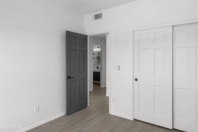 unfurnished bedroom featuring wood-type flooring and a closet