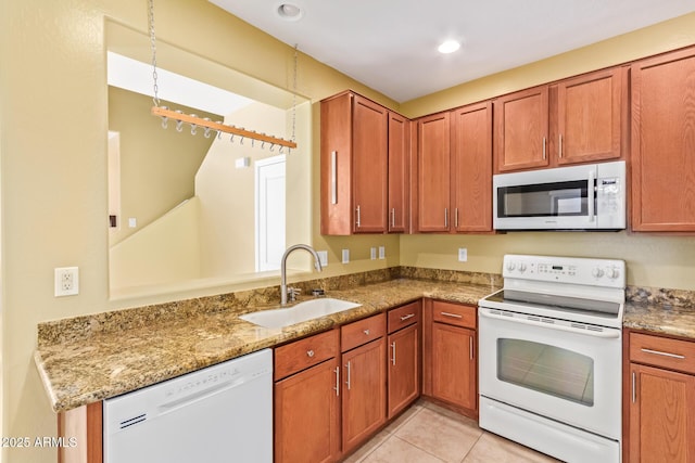 kitchen featuring white appliances, light tile patterned floors, light stone counters, and sink