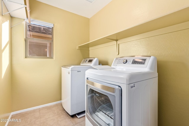 clothes washing area featuring light tile patterned floors and washer and clothes dryer