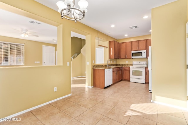 kitchen featuring white appliances, light stone counters, sink, light tile patterned flooring, and ceiling fan with notable chandelier