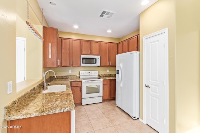 kitchen with white appliances, light tile patterned floors, light stone counters, and sink