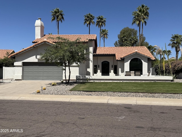 mediterranean / spanish-style home featuring a garage, stucco siding, a chimney, a tiled roof, and driveway