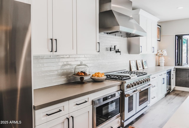 10266 E Caron St, Scottsdale, AZ 85258 - kitchen featuring stainless steel appliances, wall chimney exhaust hood, white cabinetry, tasteful backsplash, and recessed lighting