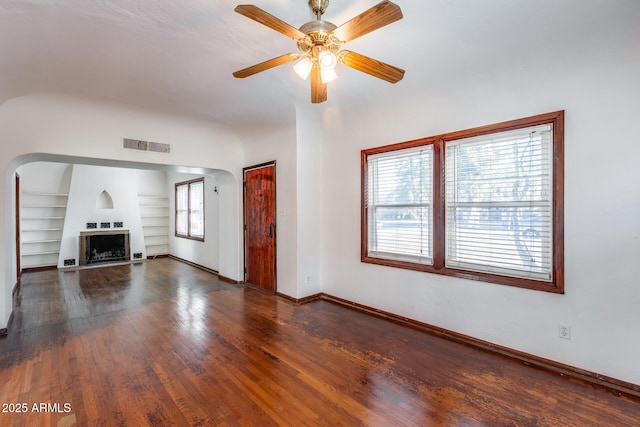 unfurnished living room with ceiling fan, dark hardwood / wood-style flooring, and built in features