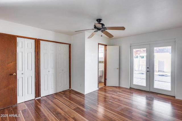 unfurnished bedroom featuring ensuite bathroom, wood-type flooring, access to outside, french doors, and multiple closets