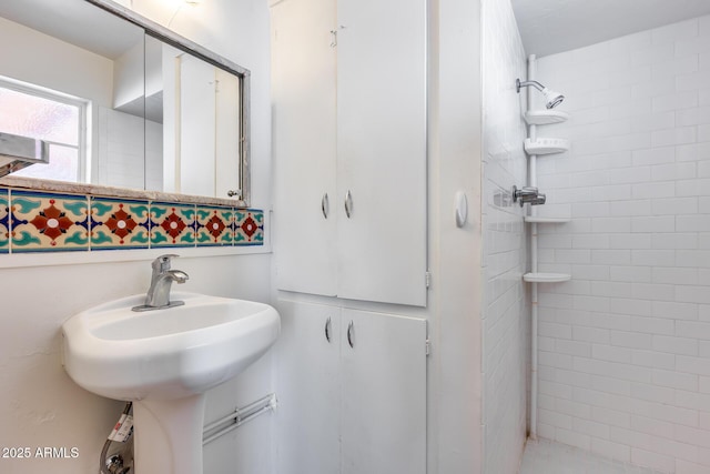 bathroom featuring sink and a tile shower