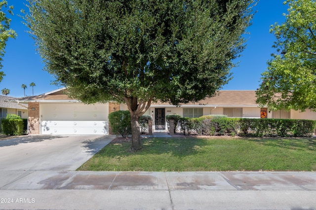 single story home with an attached garage, brick siding, driveway, stucco siding, and a front lawn