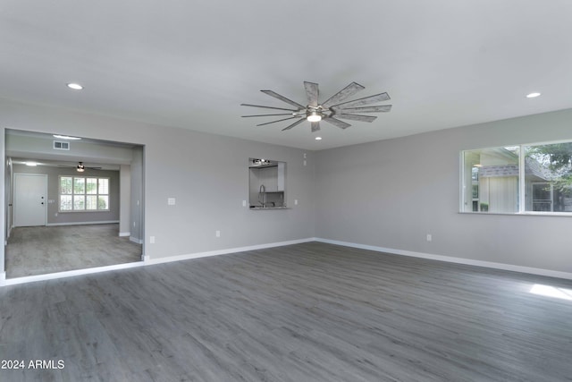 unfurnished room featuring dark wood-style floors, a ceiling fan, and baseboards