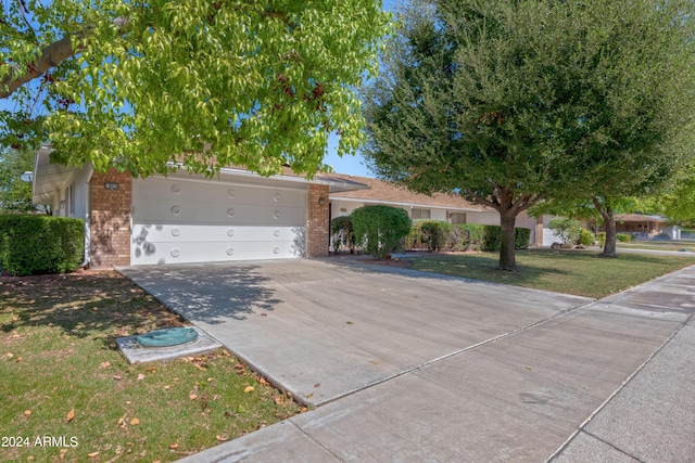 view of front facade with a front lawn, concrete driveway, brick siding, and an attached garage