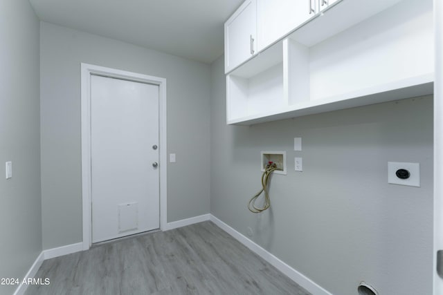 clothes washing area with cabinet space, baseboards, washer hookup, and light wood-style flooring