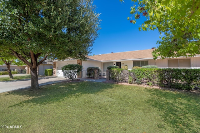 ranch-style home featuring a front lawn, concrete driveway, and an attached garage