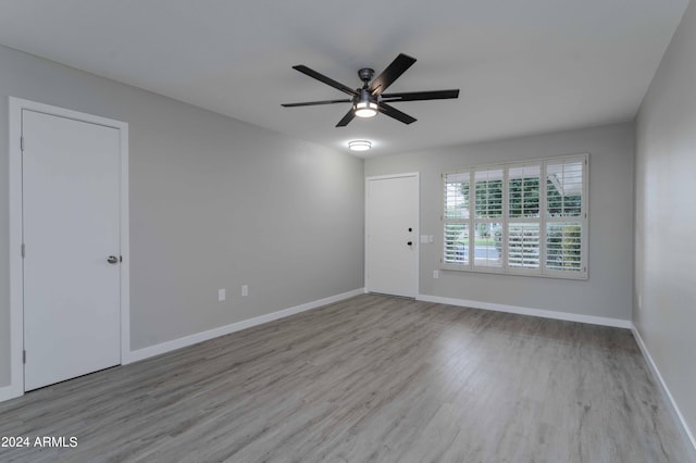 spare room featuring light wood finished floors, ceiling fan, and baseboards