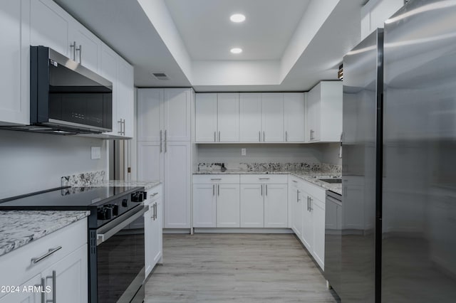 kitchen featuring light stone counters, stainless steel appliances, visible vents, light wood-style floors, and white cabinetry