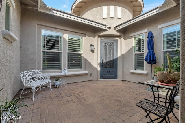 entrance to property featuring a patio area and stucco siding