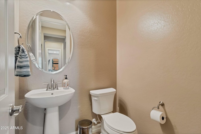 bathroom featuring toilet and a textured wall