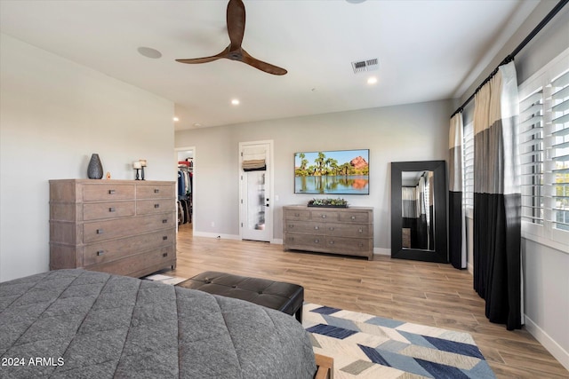 bedroom featuring ceiling fan, a spacious closet, light hardwood / wood-style floors, and a closet