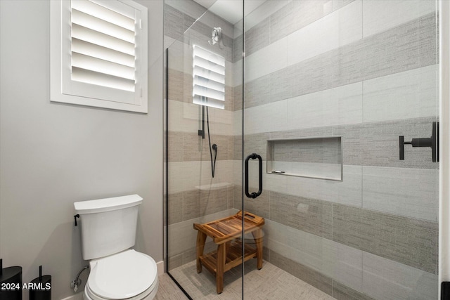 bathroom featuring a shower with shower door and toilet