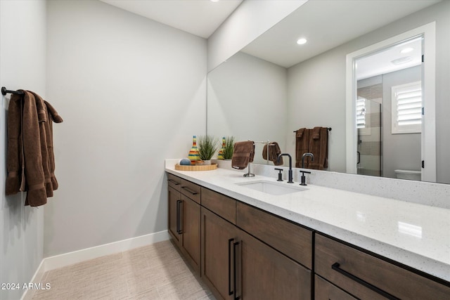 bathroom featuring a shower with door, vanity, and toilet