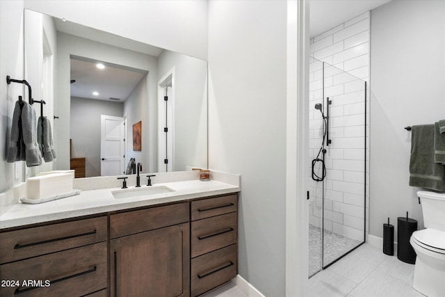 bathroom with vanity, tile patterned flooring, toilet, and a tile shower