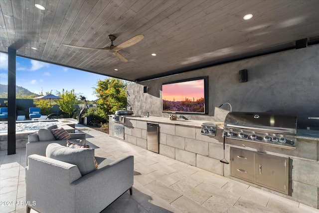 patio terrace at dusk featuring exterior kitchen, ceiling fan, a swimming pool, and grilling area