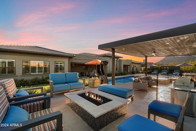 patio terrace at dusk featuring a grill, an outdoor living space with a fire pit, and ceiling fan