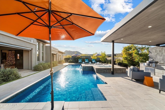 view of swimming pool with exterior kitchen, a patio, pool water feature, and a grill