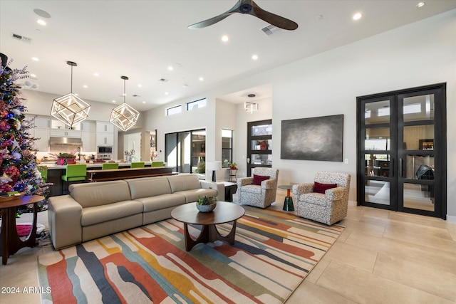 living room featuring light tile patterned floors, ceiling fan, and a high ceiling