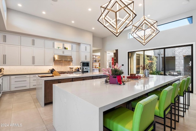 kitchen featuring pendant lighting, white cabinets, a kitchen bar, stainless steel appliances, and a spacious island