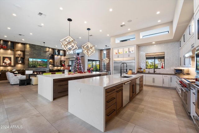 kitchen featuring sink, a spacious island, white cabinets, decorative light fixtures, and stainless steel dishwasher