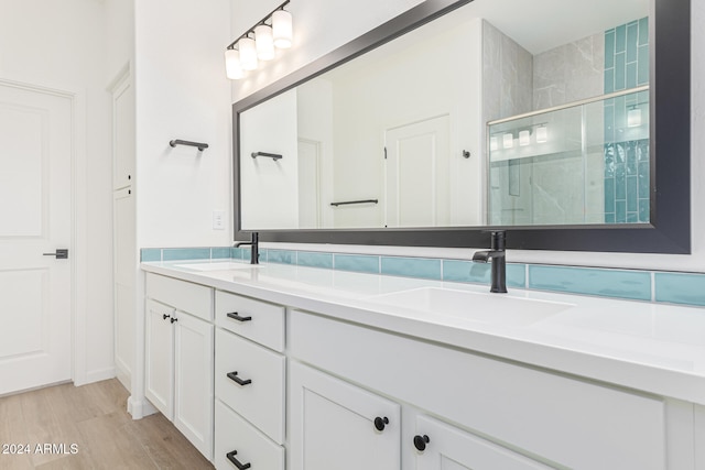 bathroom with wood-type flooring, vanity, a shower with door, and decorative backsplash