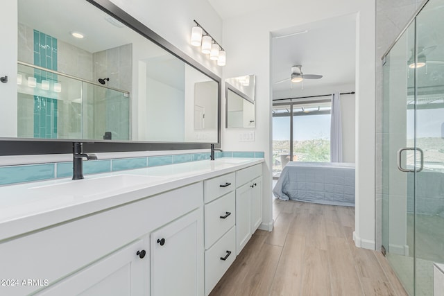 bathroom featuring hardwood / wood-style floors, a shower with shower door, vanity, and ceiling fan