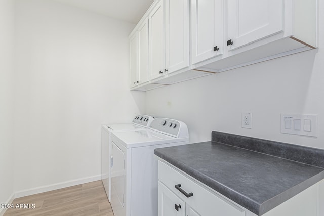 washroom featuring light hardwood / wood-style floors, washing machine and dryer, and cabinets