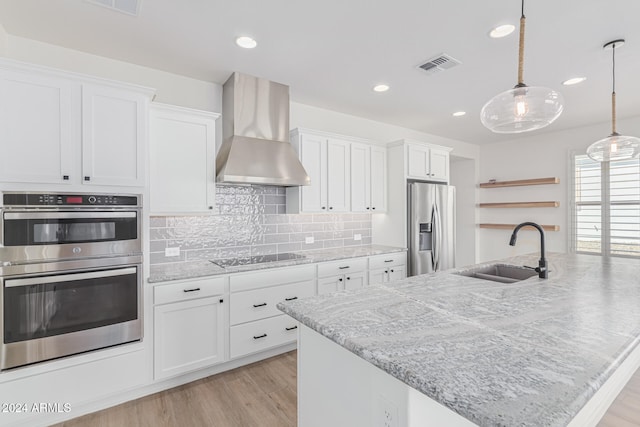 kitchen with wall chimney exhaust hood, hanging light fixtures, appliances with stainless steel finishes, and white cabinetry