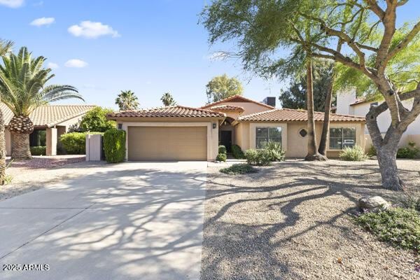 5450 E Paradise Ln, Scottsdale, AZ 85254 - mediterranean / spanish-style house featuring an attached garage, concrete driveway, a tile roof, and stucco siding