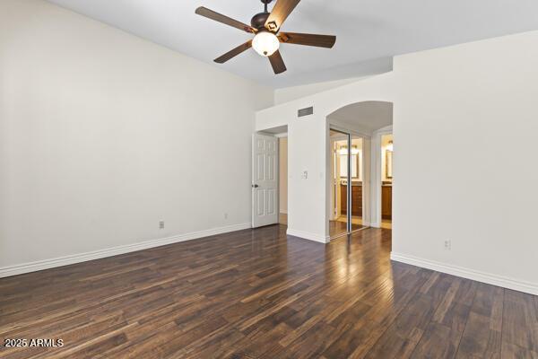 5450 E Paradise Ln, Scottsdale, AZ 85254 - empty room with arched walkways, a ceiling fan, and dark wood-style flooring