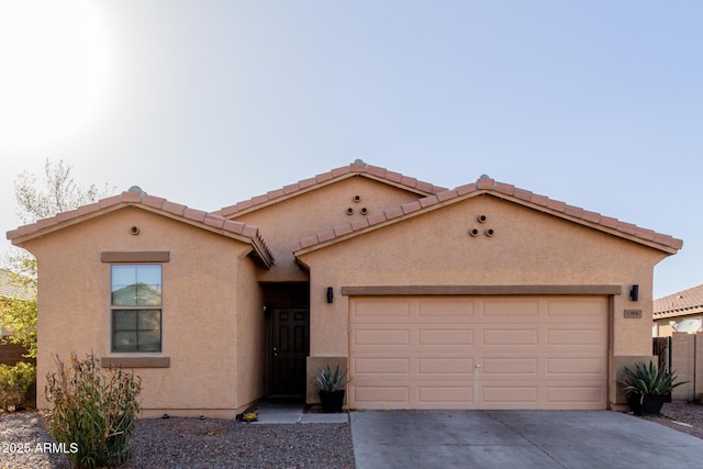 view of front of house featuring an attached garage, fence, a tile roof, concrete driveway, and stucco siding