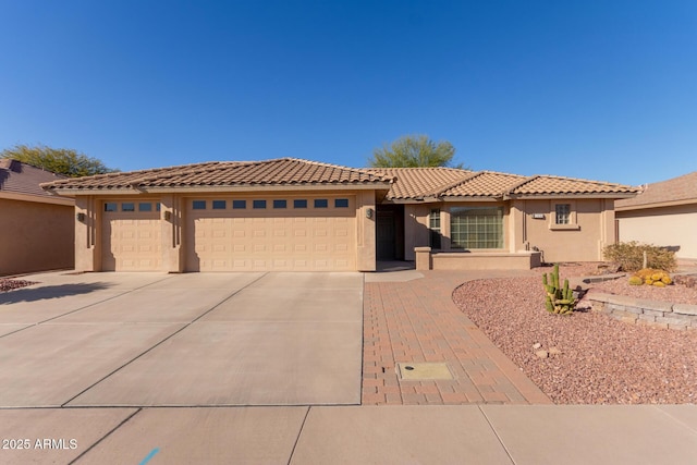 view of front of house featuring driveway, a tiled roof, an attached garage, and stucco siding