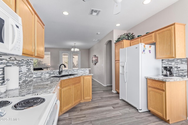 kitchen with arched walkways, a peninsula, white appliances, a sink, and visible vents