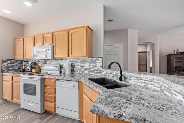 kitchen featuring light brown cabinets, white appliances, a sink, and visible vents