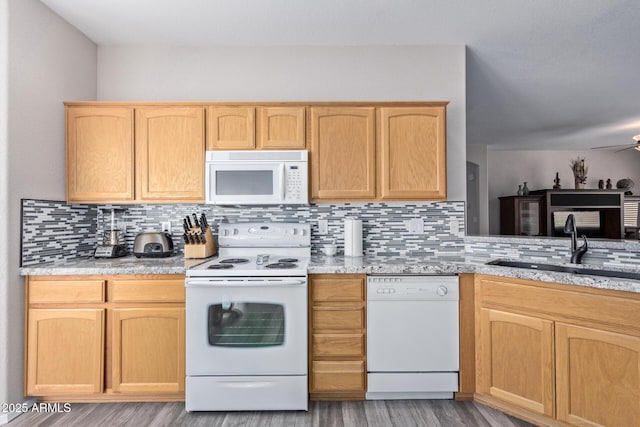 kitchen with light stone counters, tasteful backsplash, light brown cabinetry, a sink, and white appliances