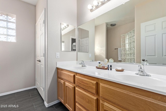 full bathroom with a sink, baseboards, and double vanity