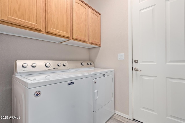 washroom with cabinet space, baseboards, and independent washer and dryer