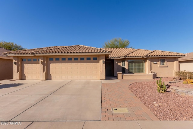 mediterranean / spanish house with a tile roof, driveway, an attached garage, and stucco siding