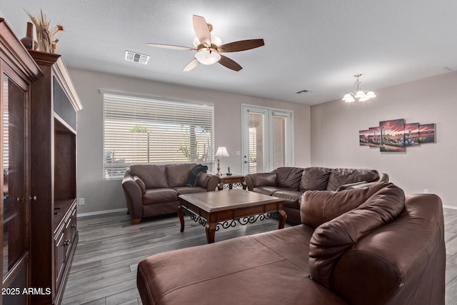 living area with baseboards, visible vents, wood finished floors, and ceiling fan with notable chandelier